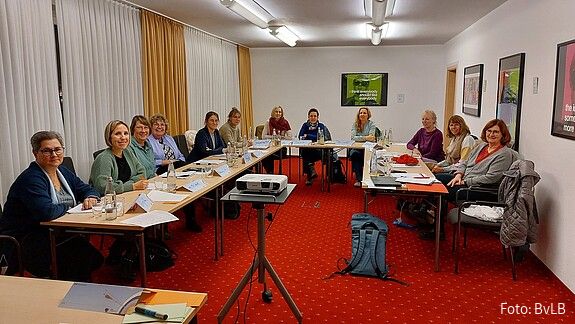 In einem Seminarraum sitzen Frauen an Tischen und diskutieren miteinander