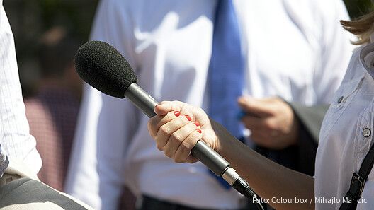 Eine Frau hält einer anderen Person ein Mikrofon hin