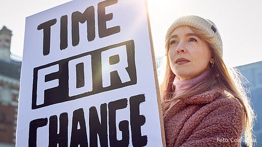 Eine junge Frau hält bei einer Demonstration ein Plakat mit der Aufschrift "Time for Change" hoch.