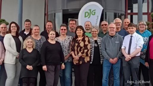 Eine Menschengruppe steht mit Blick zur Kamera vor einem Hoteleingang