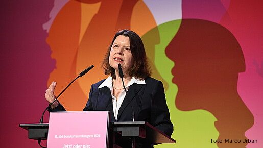 Eine Frau steht hinter einem Rednerpult und spricht in das Mikrofon