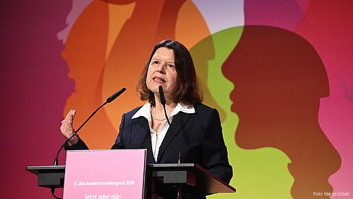 Eine Frau steht hinter einem Rednerpult und spricht in das Mikrofon