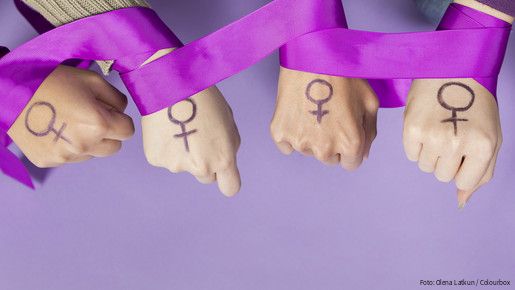 Vier Frauenhände mit einem aufgemalten Frauen-Symbol, ein violettes Band ist um die Handgelenke gelegt