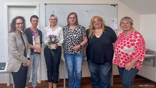 Eine Gruppe Frauen steht vor einem Whiteboard und blicken in Richtung Kamera